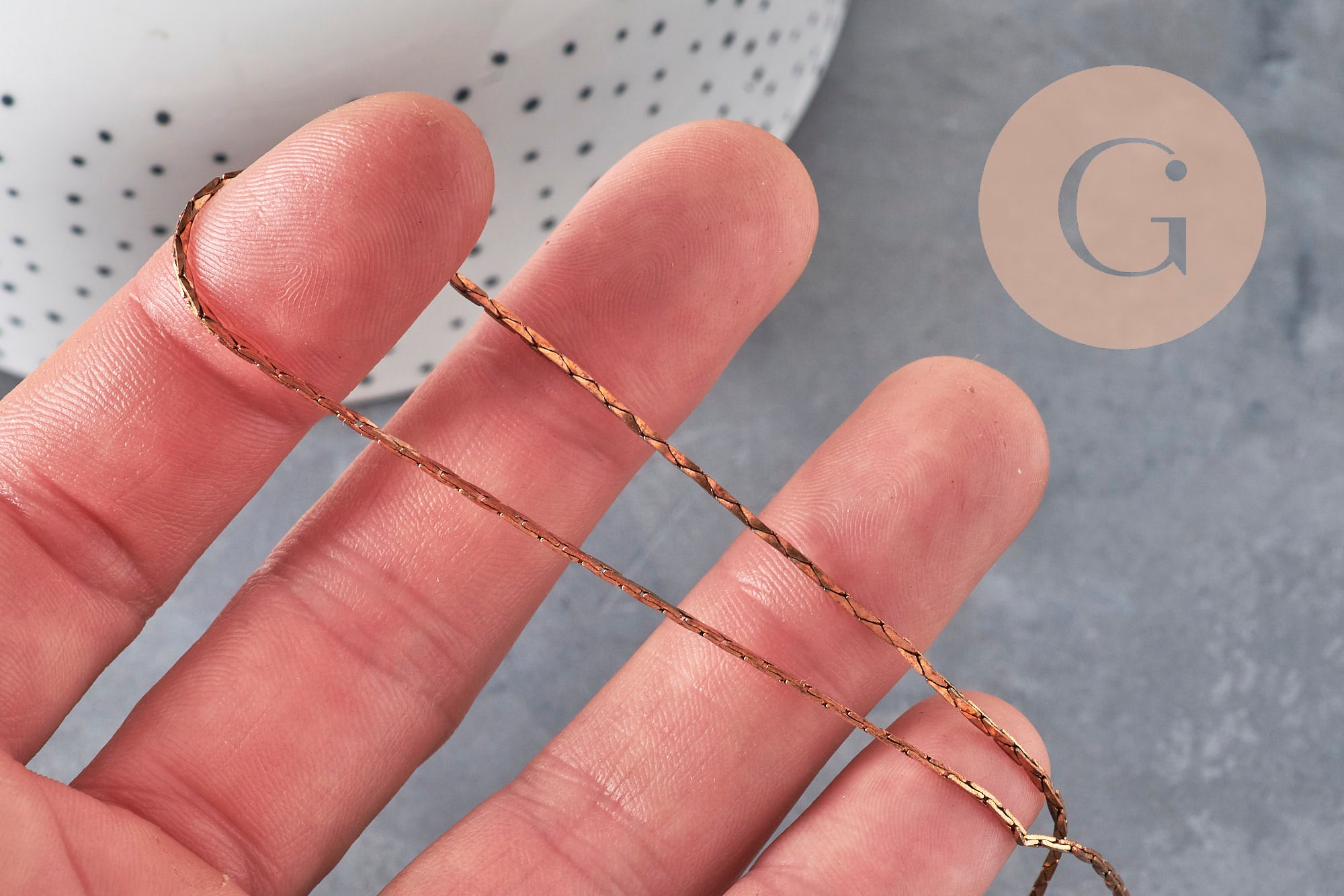 Chaîne forçat fine en laiton brut de 1mm tenue entre les doigts pour la création de bijoux fantaisie DIY.