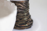 EP-Chaine fine maille plate noire reflets dorés 1.5mm, X 5 mètres G0554