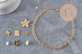 Kit collier DIY avec chaîne en acier inoxydable doré, breloques fleur, cœur, arbre de vie et perles sur fond gris.
