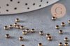 Perles à écraser rondelles en laiton couleur bronze 3x2mm, dispersées sur une surface grise.